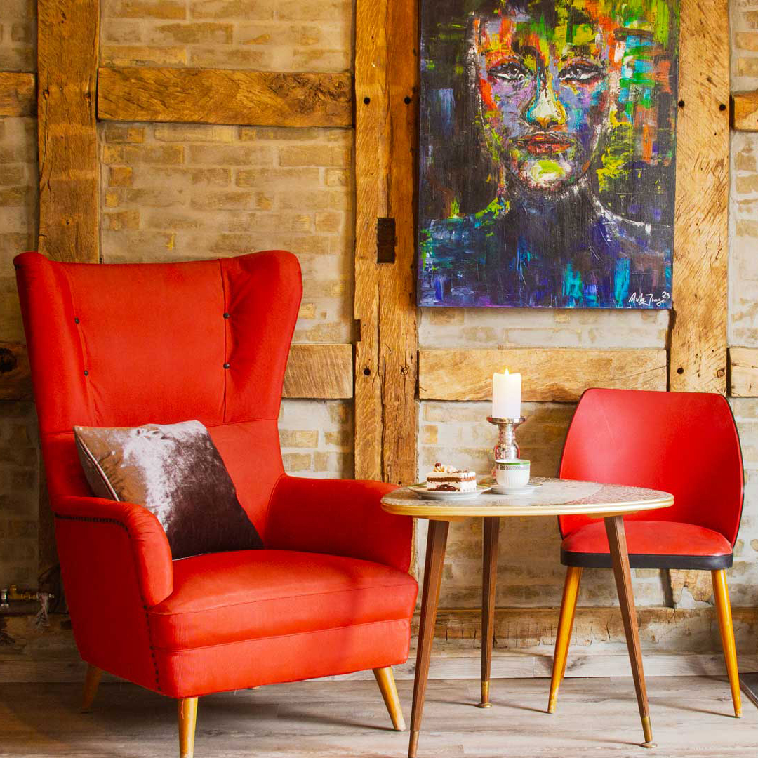 Gemütliche Sitzecke im Café Kunsthauus mit rotem Sessel und Kunstbild