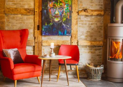 Gemütliche Sitzecke im Café Kunsthauus mit rotem Sessel, Kamin und Kunstbild