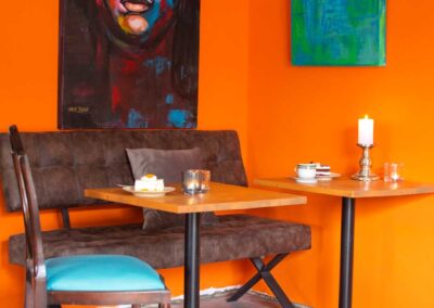 Tisch im Café Kunsthauus vor orangefarbener Wand mit moderner Kunst